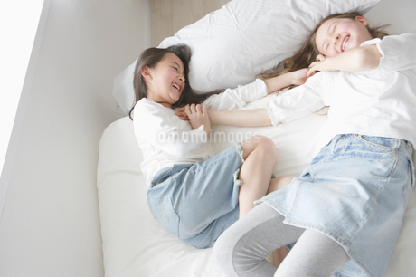 ベッド 写真はイメージです。 ベッドに寝転がってはしゃぐ二人の少女の写真素材 [FYI01892107