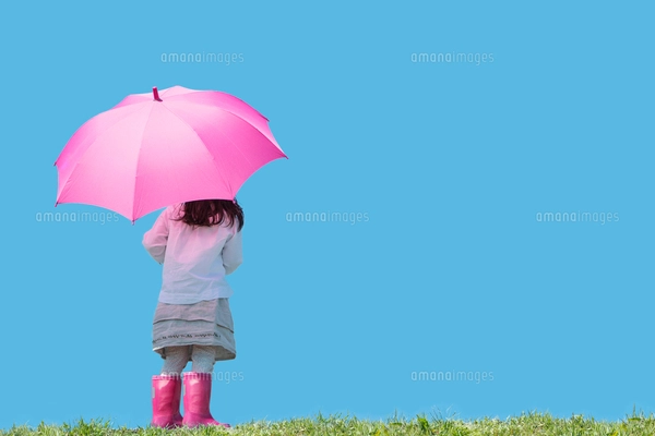 ピンクの傘と長靴の女の子の後ろ姿 雲と雨のしずくの写真素材