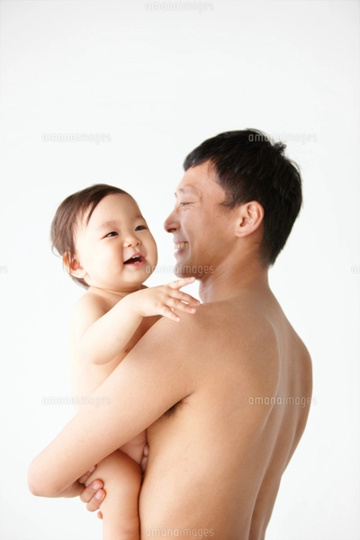 笑顔の裸の赤ちゃんを抱っこする裸のお父さんの写真素材 [FYI01382507 