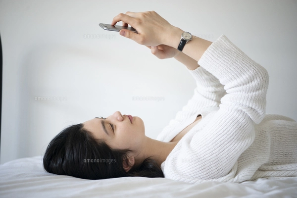 ベッドに寝転んで笑っている女性の写真素材 [FYI01708196] | ストック