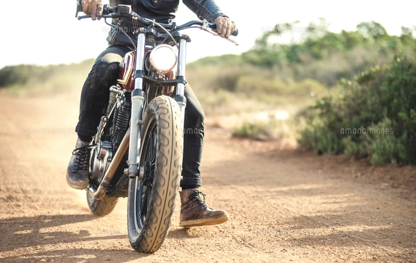 Low section view of man wearing jeans and black leather boots sitting ...