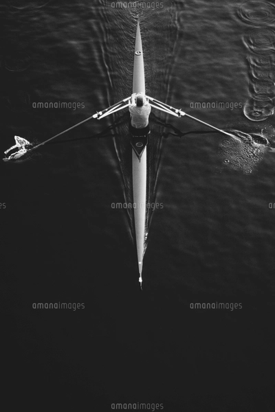 A man sculling in a single scull rowing boat, on the water. Overhead ...