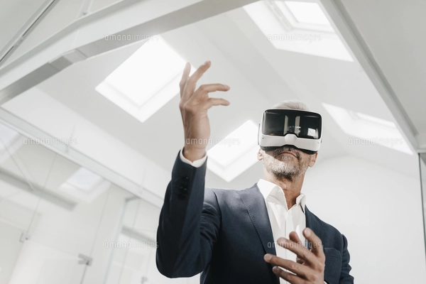 Mature businessman in office wearing VR glasses holding Rubiの写真素材 ...