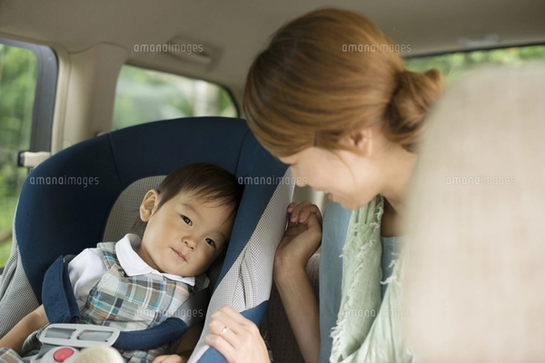 チャイルドシートに乗る子供と会話をする母親の写真素材 [FYI04547547 