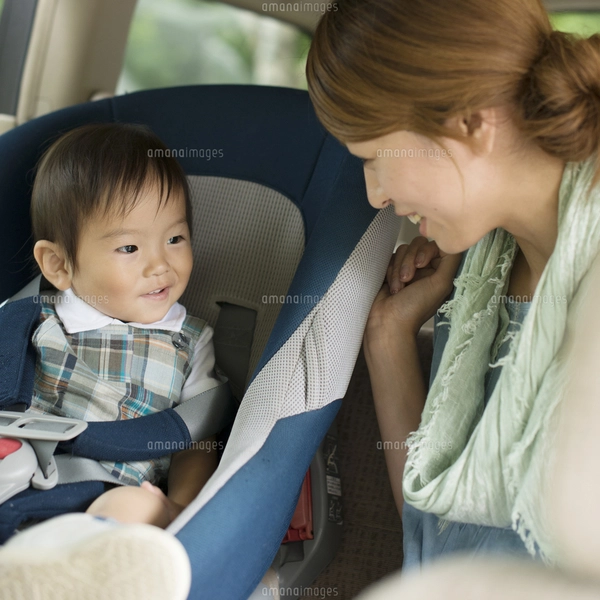 チャイルドシートに乗る子供と会話をする母親の写真素材 [FYI04547547 