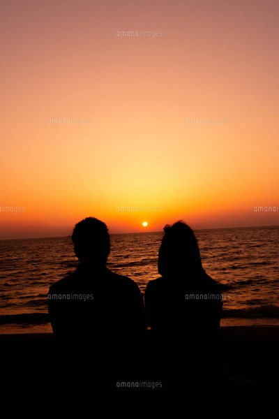 沈む夕日とカップルのシルエットの写真素材 [FYI04595525] | ストック