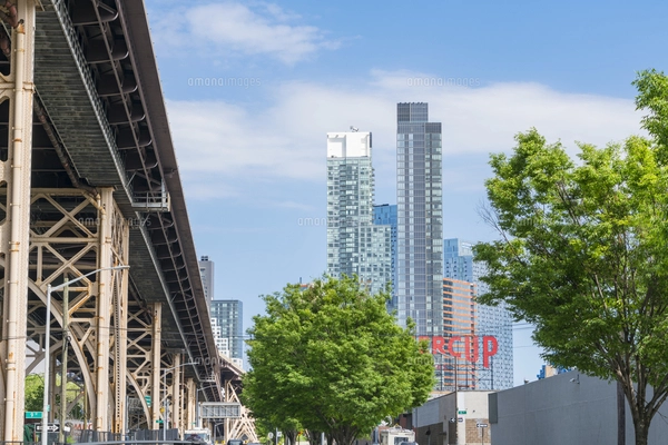 クイーンズ ボローブリッジ橋脚横の新緑越しにそびえ立つニューヨーク市 クイーンズ ロングアイランドシティー クイーンズボロープラザの新興高層