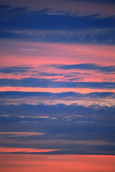 オレンジ色と雲とのグラデーションが美しい朝焼けの空の写真素材