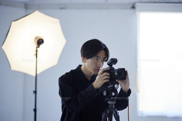 写真スタジオにて撮影を行う日本人カメラマンの男性の写真素材
