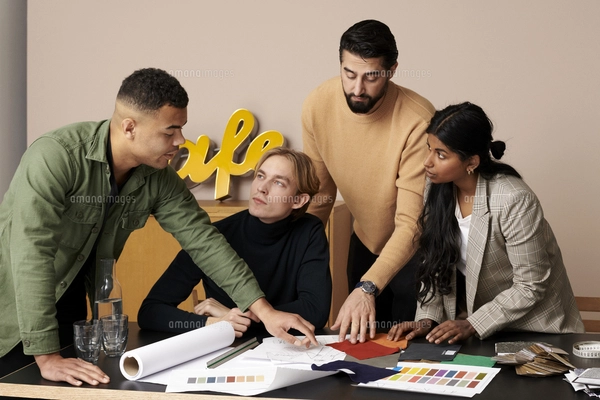 Multiracial male and female fashion designers huddling with clenched ...