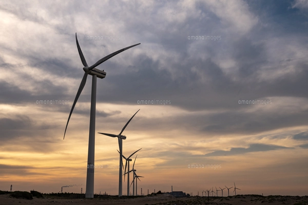 夕暮れ時の夕陽を背景にした波崎の海の砂浜の風力発電の写真素材