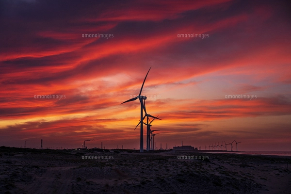 夕暮れ時の夕陽を背景にした波崎の海の砂浜の風力発電の写真素材