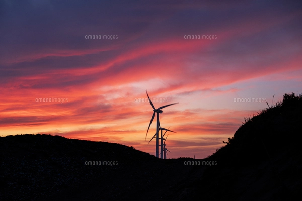 夕暮れ時の夕陽を背景にした波崎の海の砂浜の風力発電の写真素材